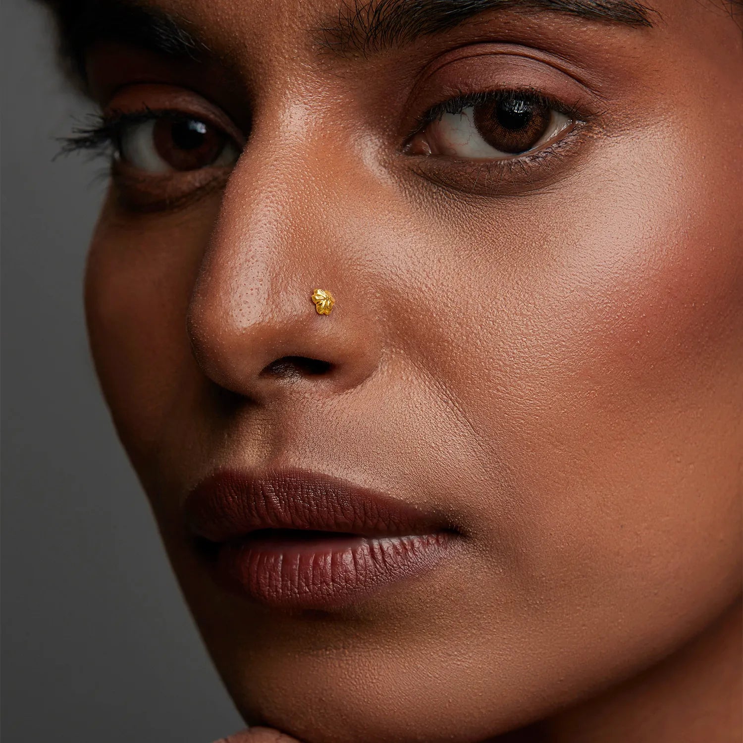 Woman wearing a minimalist 18K gold nose pin showcasing a refined side profile look