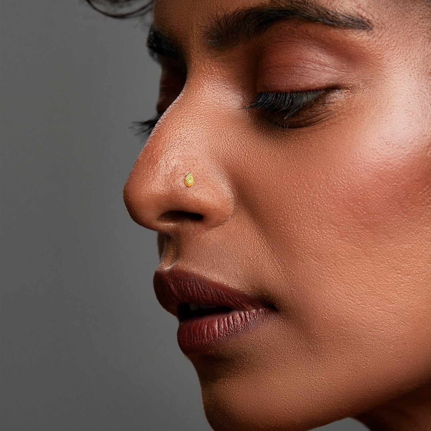 Woman wearing a minimal gold nose pin shown in side profile emphasizing an elegant and natural look
