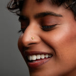 Woman smiling while wearing a small gold nose pin showing a graceful and natural everyday look