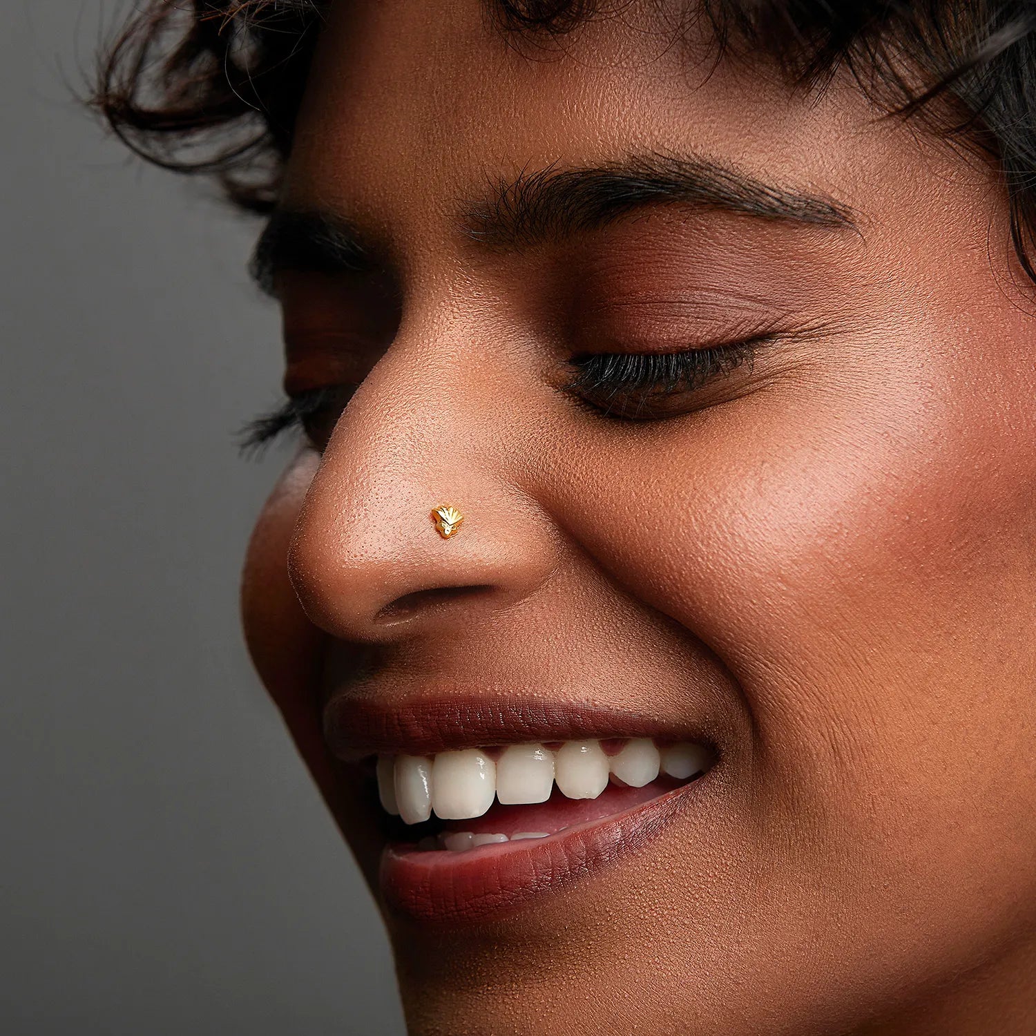 Woman smiling while wearing a small gold nose pin showing a graceful and natural everyday look