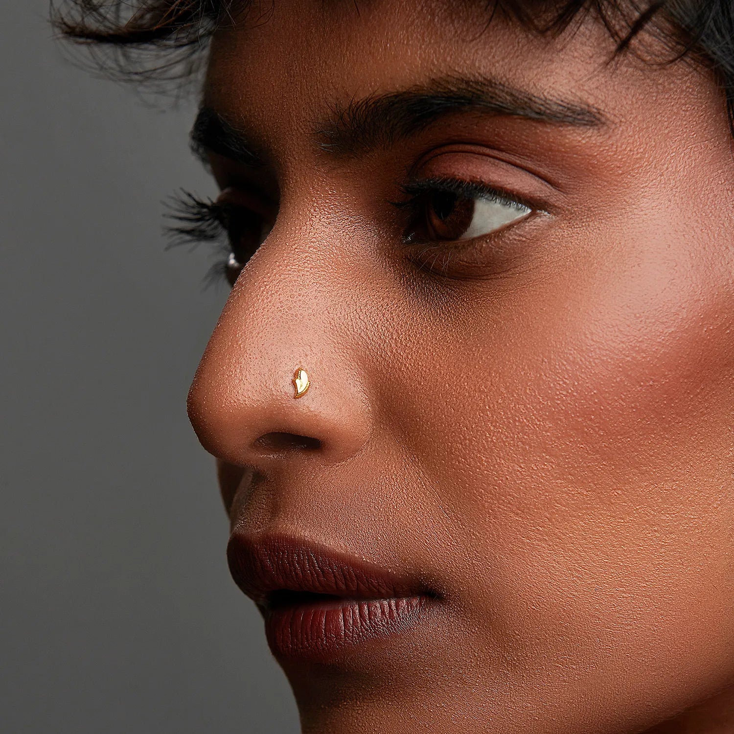 Woman wearing a delicate gold nose pin shown in side profile highlighting an elegant everyday look