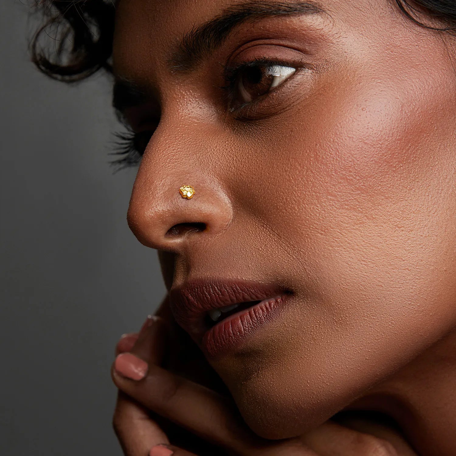 Side profile of a woman wearing a minimal gold nose pin showcasing an elegant and natural look