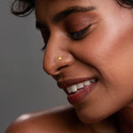 Woman wearing a minimal gold nose pin in side profile showcasing a soft elegant everyday look