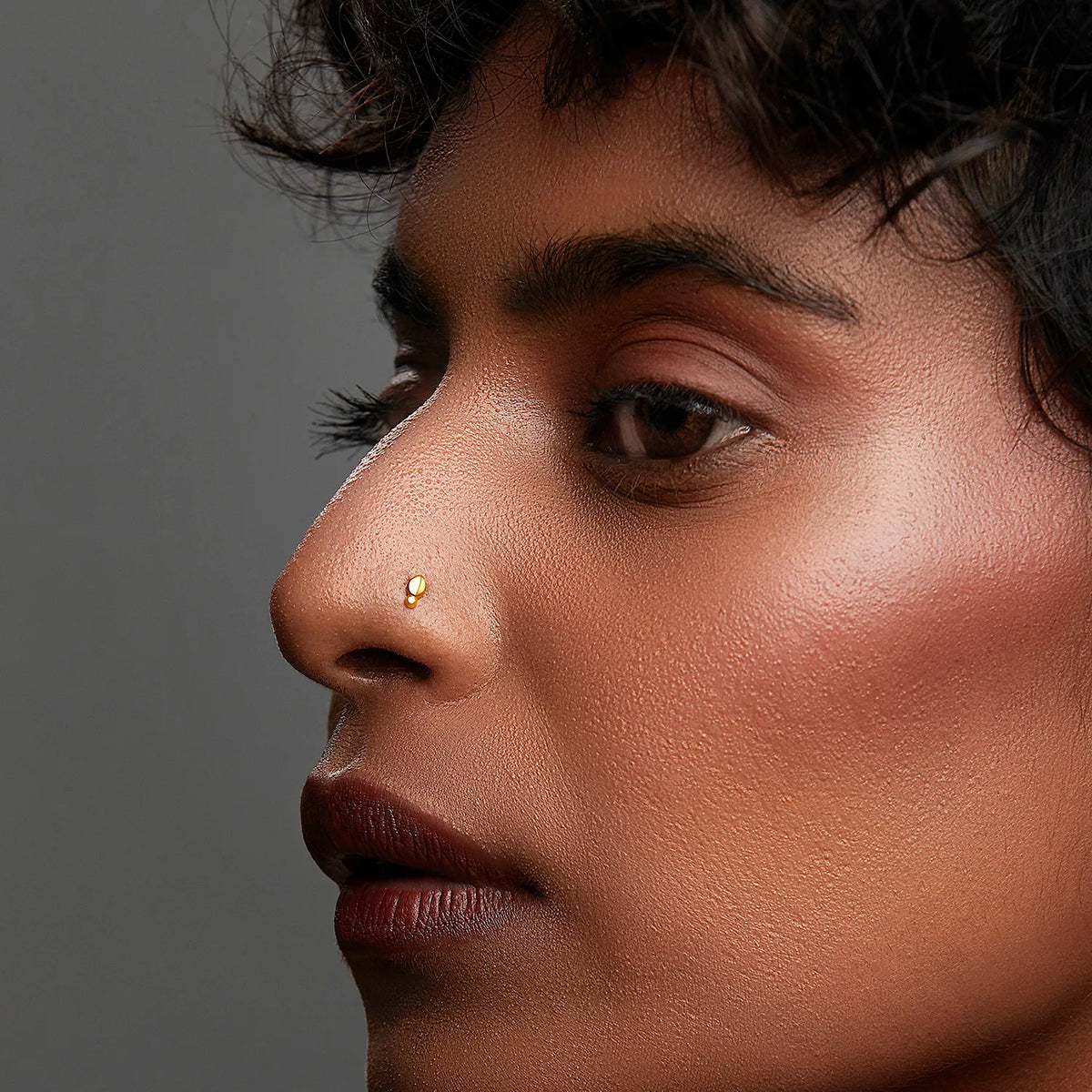 Side profile of a woman wearing a minimal gold nose pin showcasing an elegant everyday style
