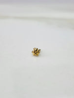 Side angle view of floral 18K gold nose pin on a white surface highlighting its compact and lightweight design