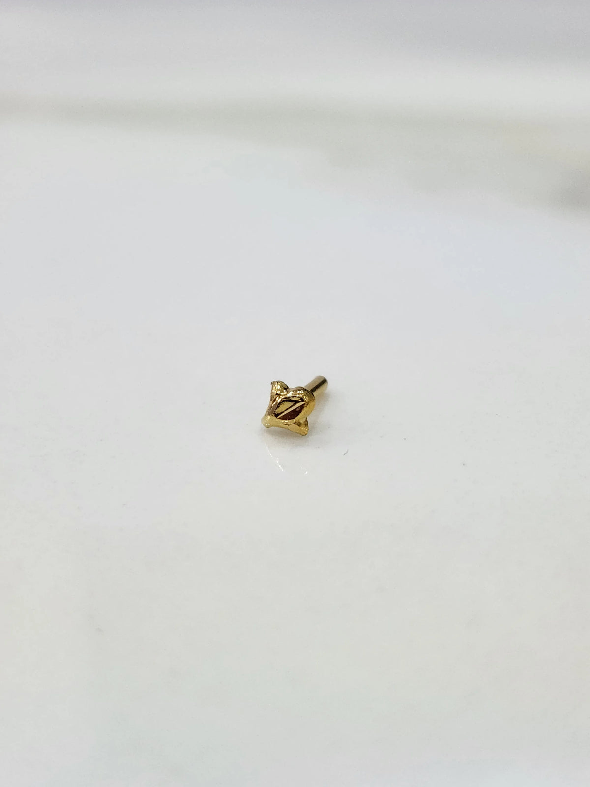 Front view of minimal 18K gold nose pin on a white background showing its petite size
