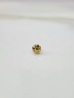 Small gold nose pin photographed on a smooth white surface highlighting its delicate design