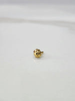 Close-up of a tiny gold nose pin placed on a white marble surface