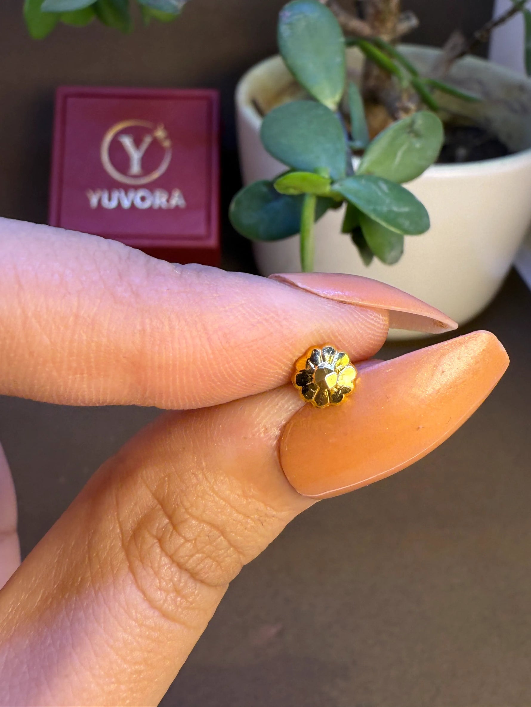 Hand holding a small gold nose pin to show its real-life size and shine