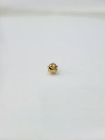 Side angled view of the small gold nose pin on a white surface highlighting its lightweight design