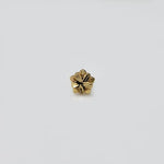 Gold flower nose pin on white surface showing detailed petal texture front view