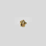 Side angle view of small floral gold nose pin placed on white surface for clarity