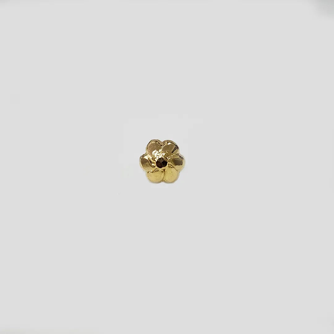 Angled view of flower inspired gold nose pin on a neutral background showing depth and craftsmanship