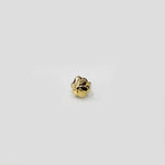 Top view of small floral gold nose pin on a light surface emphasizing minimal design