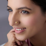 Woman wearing stylish gold nose pin showcasing delicate floral motif and traditional elegance