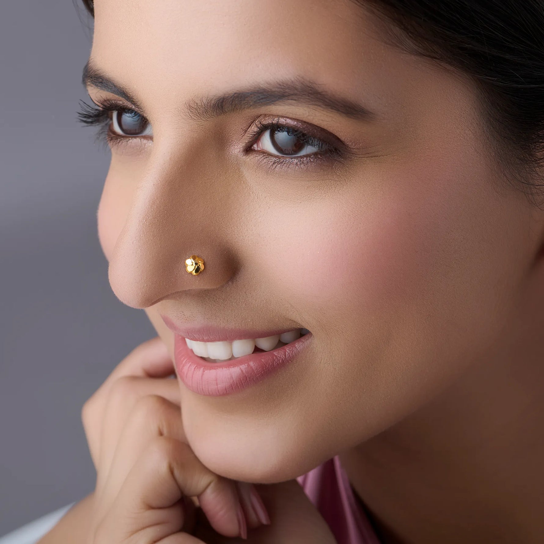 Woman wearing stylish gold nose pin showcasing delicate floral motif and traditional elegance