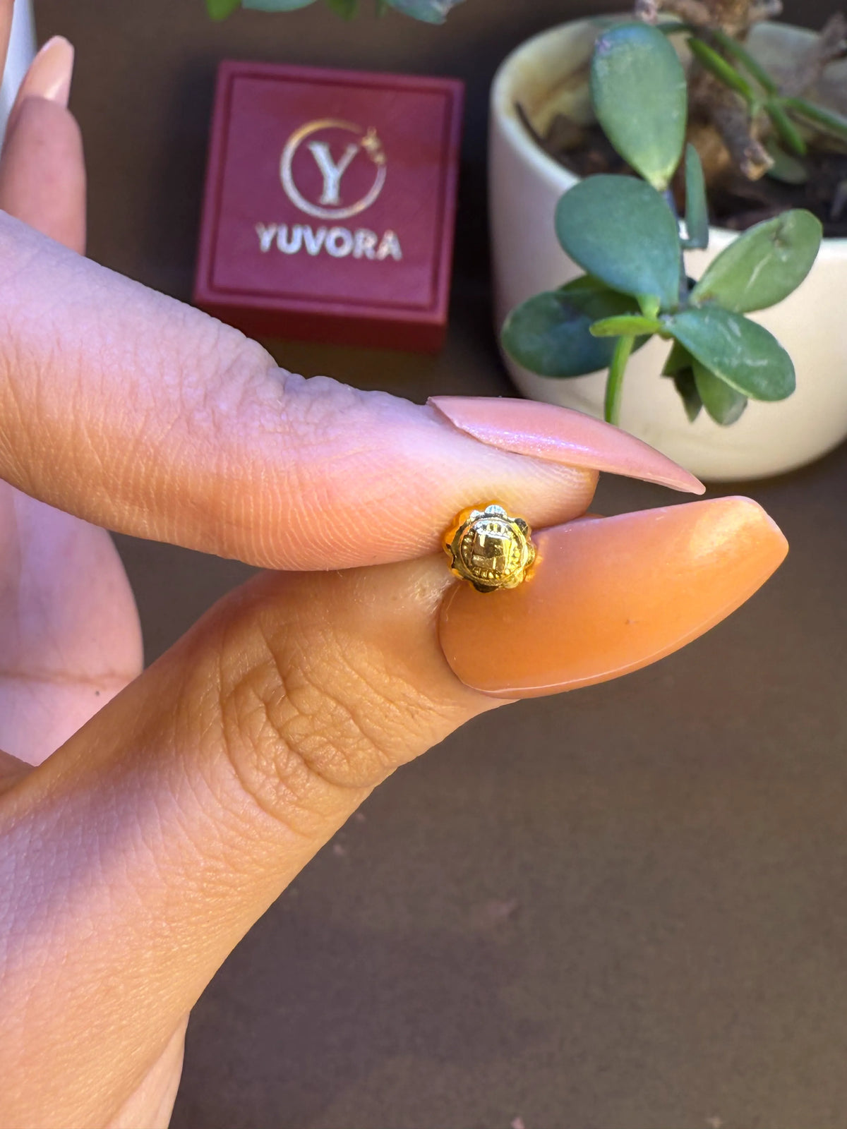 Hand holding Swastik Bloom 18K Nose Pin Gold highlighting size and fine craftsmanship