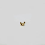 Close up of crescent gold nose pin on white surface highlighting polished shine and smooth edges