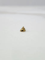 Side view of a tiny gold nose pin on a white surface highlighting its pointed design and subtle shine