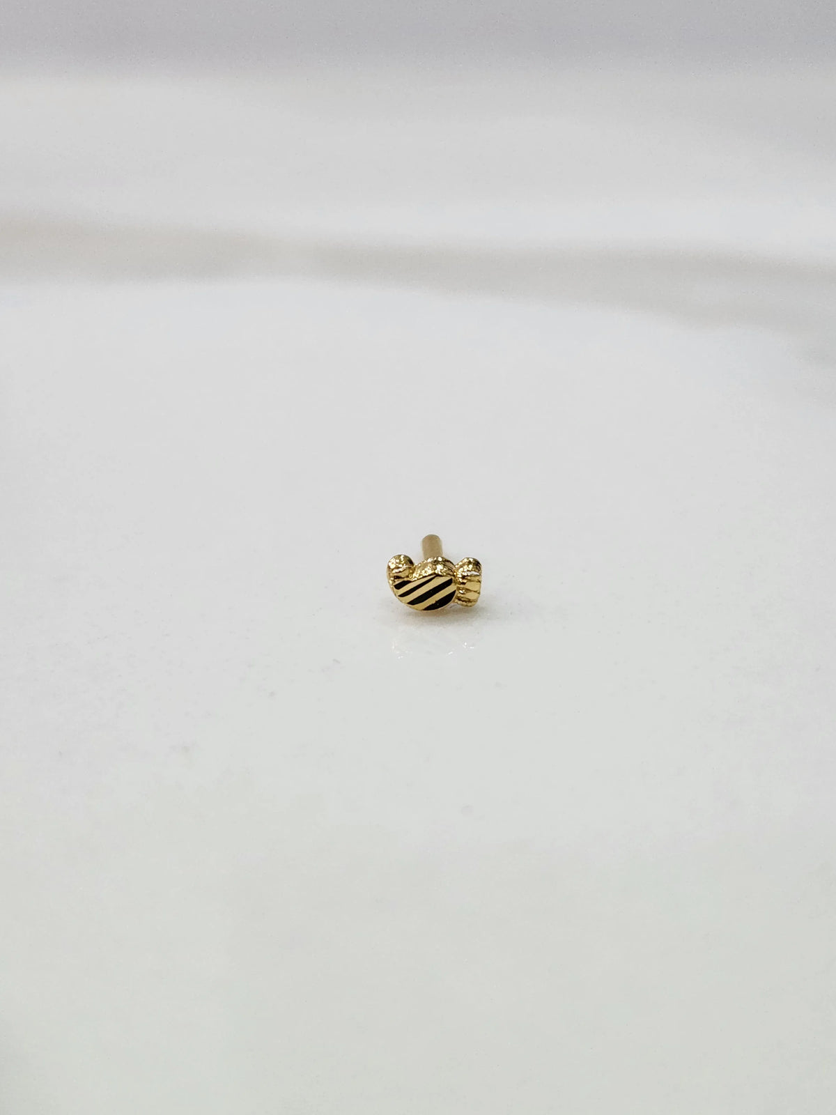 Tiny gold nose pin placed on a white background displaying its compact size and fine craftsmanship