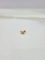 Side view of a delicate gold nose pin on a white surface highlighting its smooth edges and lightweight form