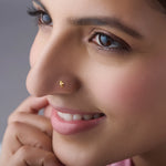 Woman smiling while wearing a small 18K gold nose pin styled for everyday elegance