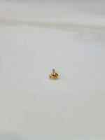 Slight angled view of a tiny 18K gold nose pin on a white surface highlighting its lightweight design and polish