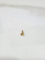 Close up of teardrop gold nose pin placed on white surface showing polished shine