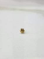 Side view of a delicate gold nose pin on a white surface emphasizing fine craftsmanship and subtle shine