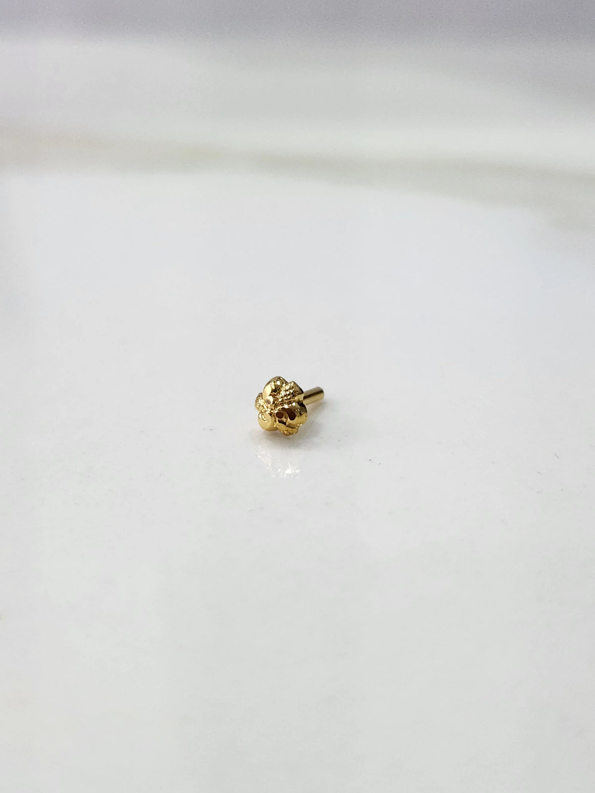 Front view of a small gold nose pin on a white background showing its compact lightweight design
