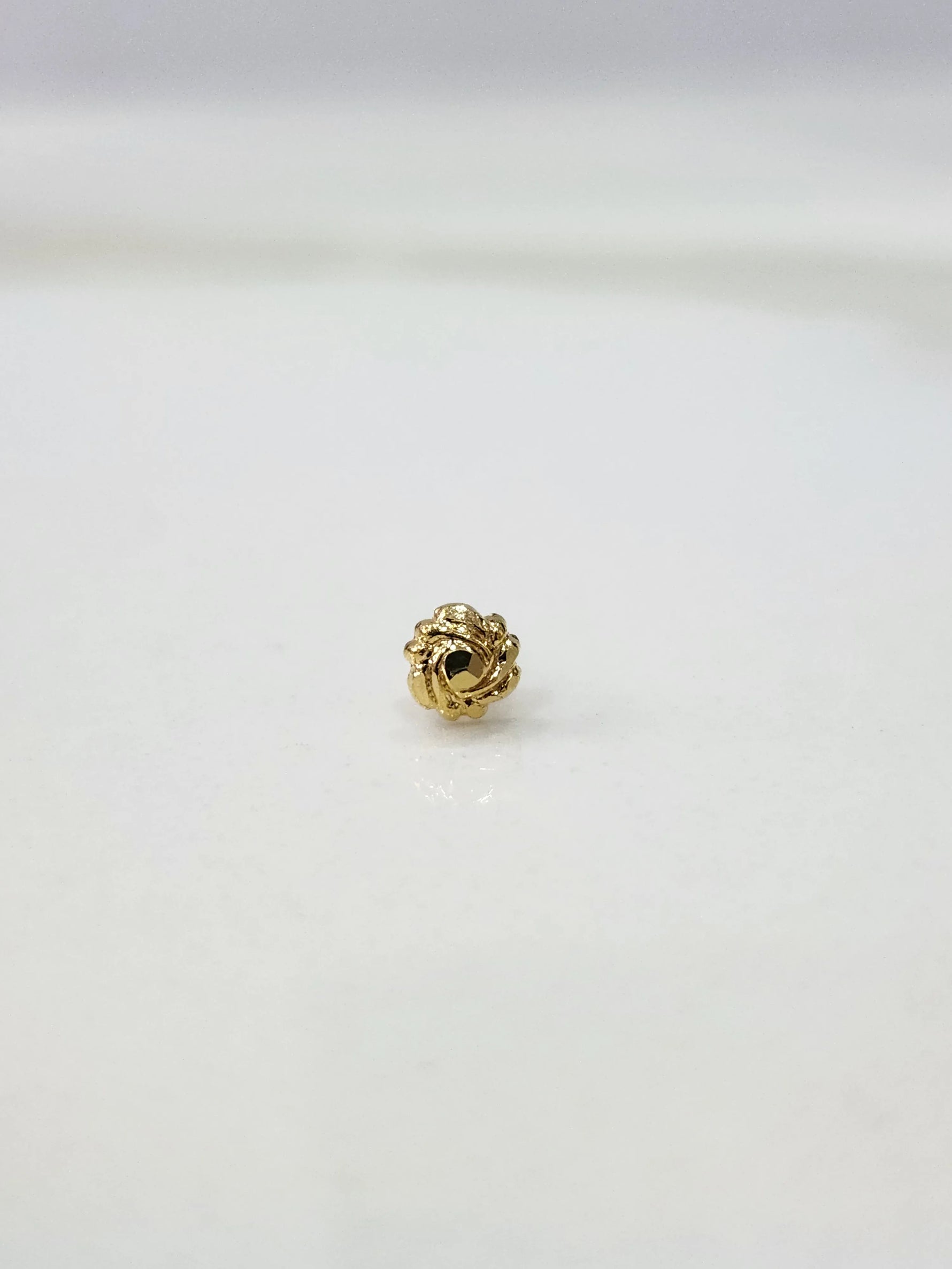 Side view of a lightweight gold nose pin on a white surface emphasizing fine craftsmanship