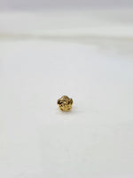 Side view of a tiny gold nose pin on a white surface displaying its lightweight build and subtle shine