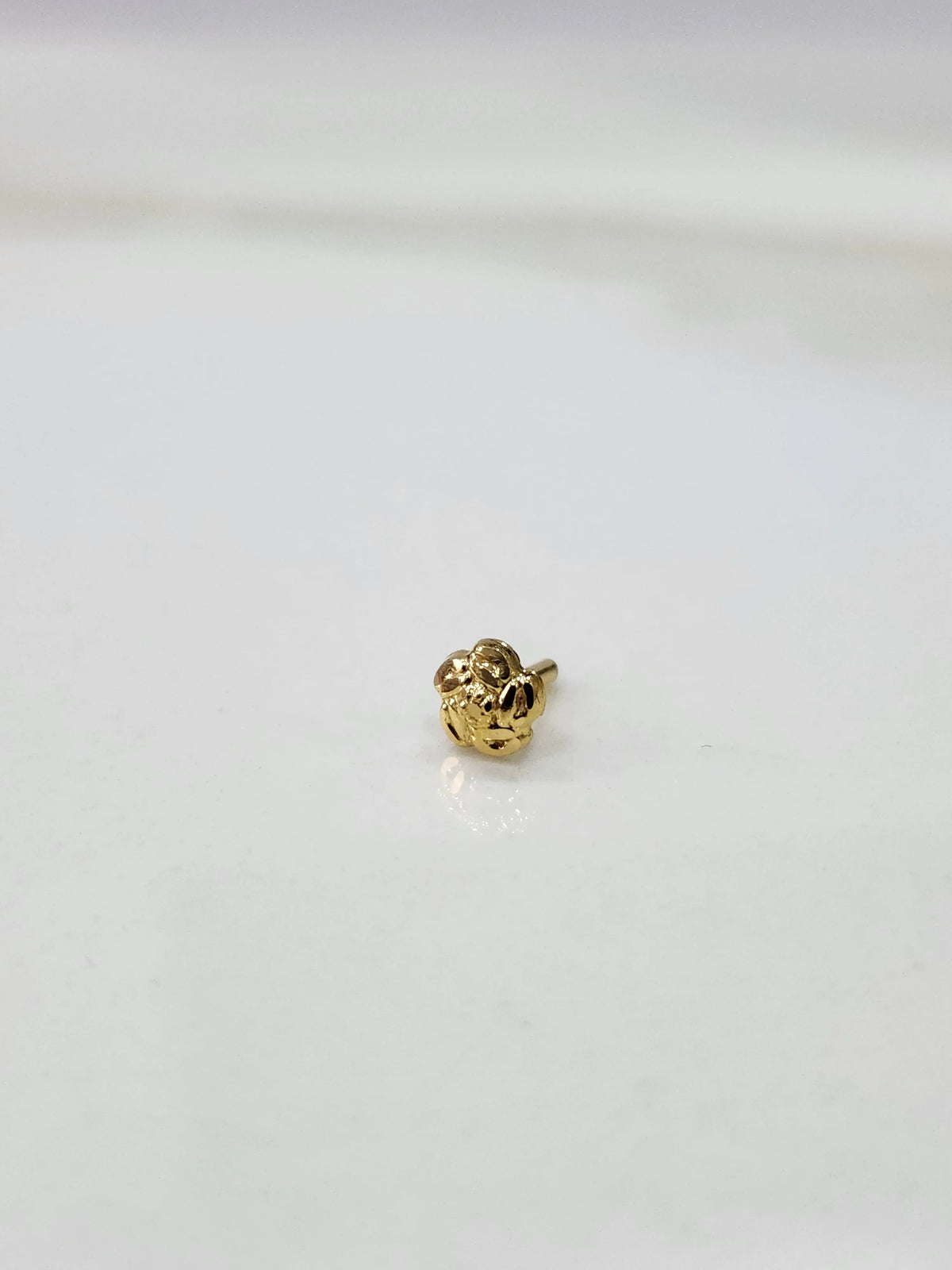 Front view of a small gold nose pin on a white background showing compact size and clean detailing