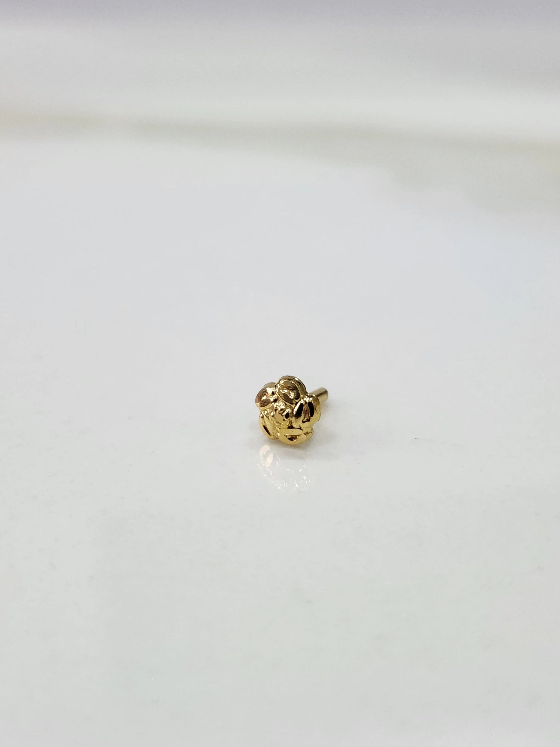 Front view of a small gold nose pin on a white background showing compact size and clean detailing