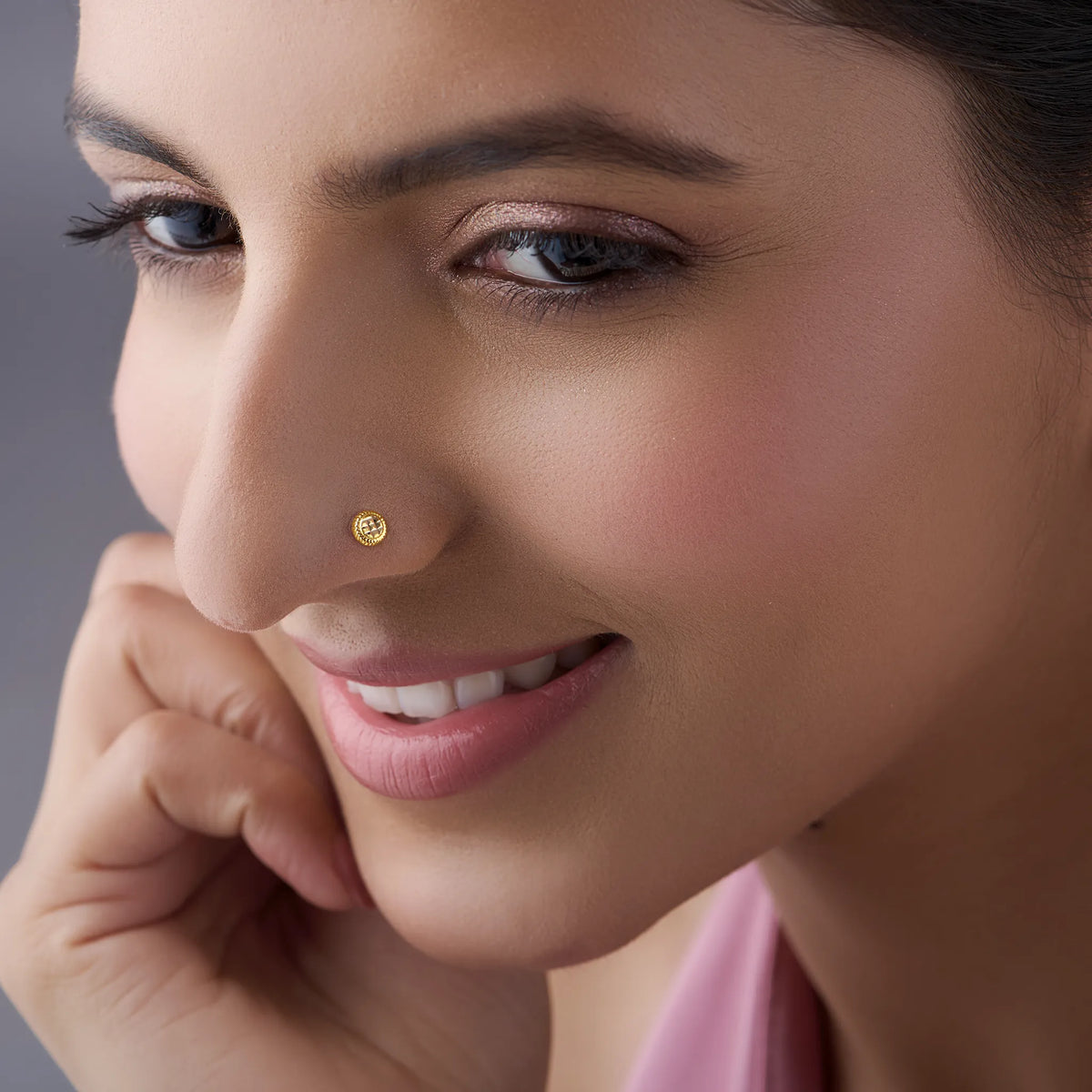 Woman wearing stylish gold nose pin design showcasing minimal round motif and graceful traditional look