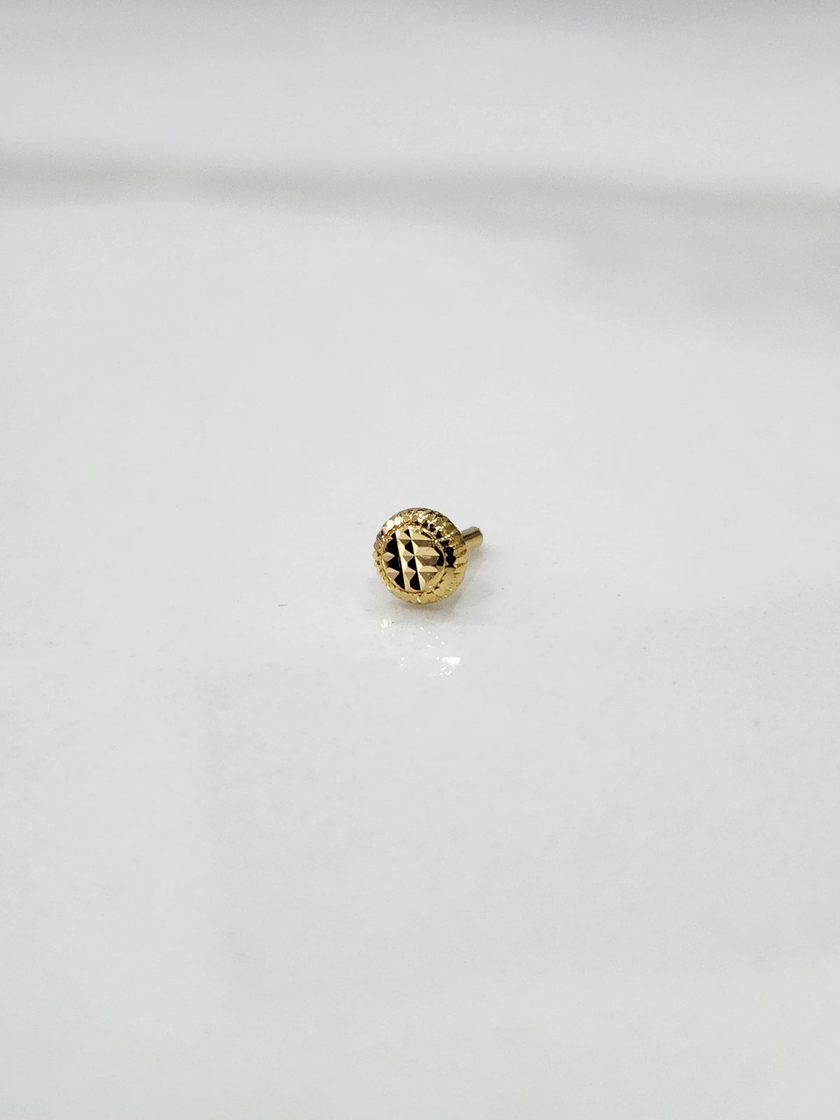 Side view of handcrafted 18k circular gold nose pin design featuring polished finish and intricate detailing