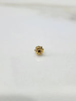 Side view of a delicate gold nose pin on a white surface highlighting fine detailing and shape