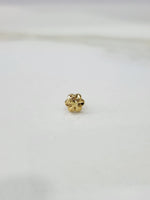 Small gold nose pin placed on a white background showing fine detailing and compact round shape