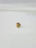 Side view of a tiny gold nose pin on a white surface highlighting its subtle shine and minimal form