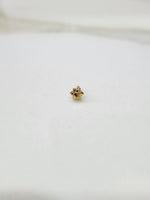 Side view of a small gold nose pin on a white surface highlighting its minimalist design and smooth shine