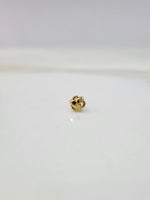 Side view of the floral 18K gold nose pin on a white surface showing depth and craftsmanship