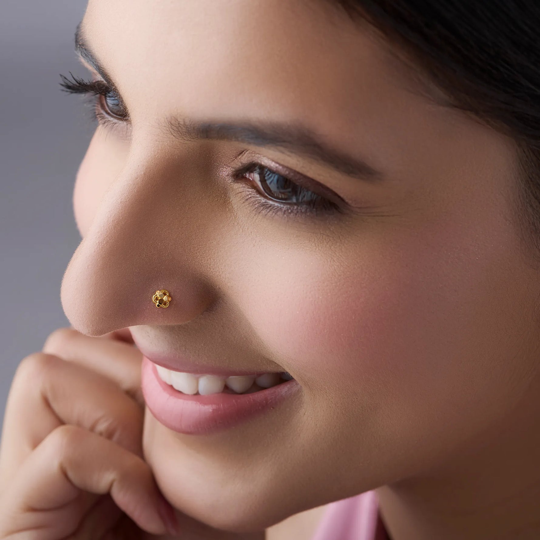 Front profile of a woman wearing a floral 18K gold nose pin showing elegant everyday styling