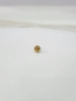 Side view of a minimal gold nose pin on a white surface highlighting its subtle shine and neat finish