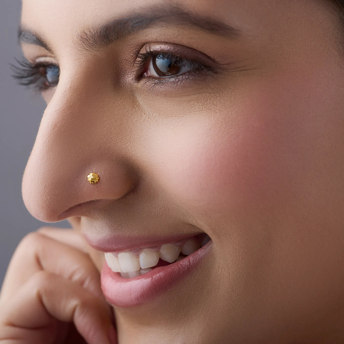 Woman wearing a delicate gold nose pin in a close profile view showcasing an elegant everyday look