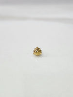 Side view of a lightweight gold nose pin on a white surface highlighting its fine craftsmanship and minimal profile