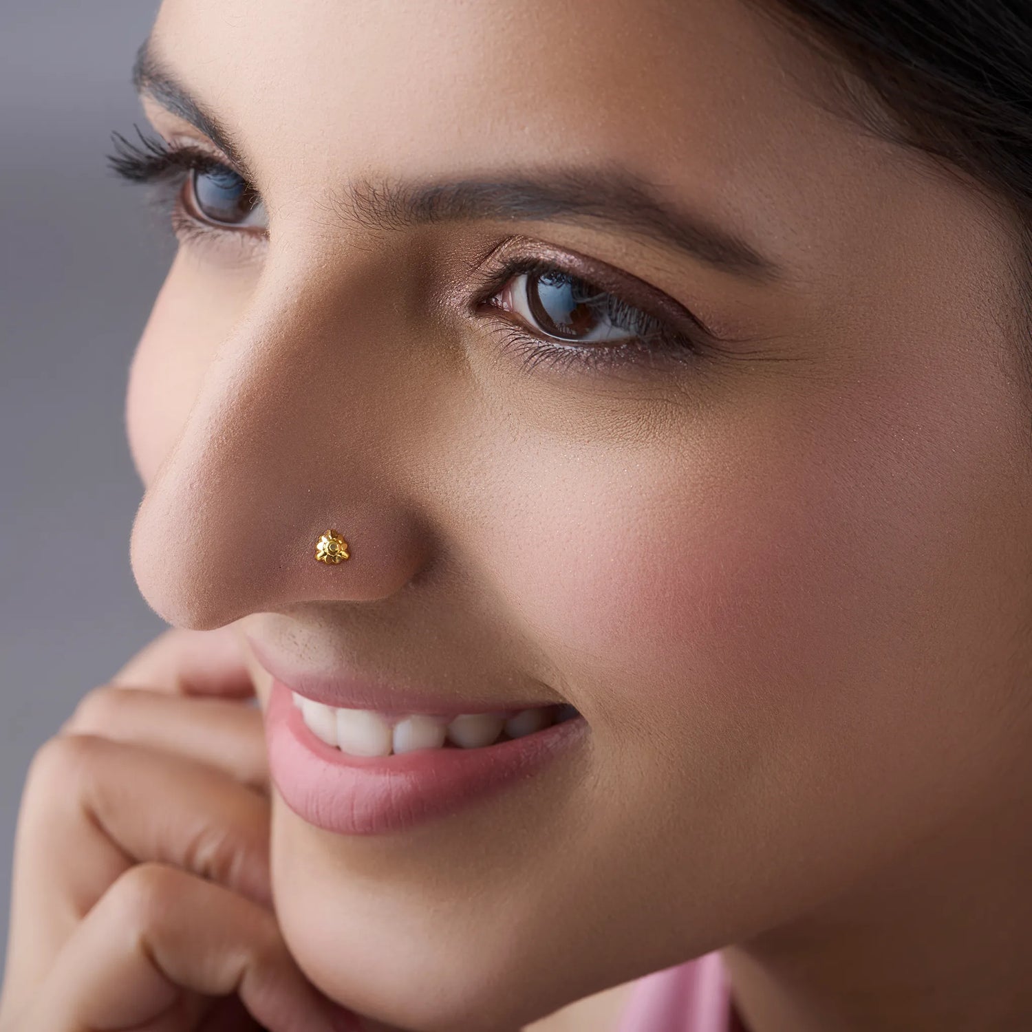 Woman wearing a small gold nose pin smiling softly showcasing an elegant everyday look