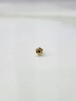 Slight side angled view of a small 18K gold nose pin placed on a white surface highlighting its subtle shine and craftsmanship