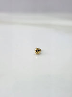 Front view of a tiny 18K gold nose pin on a white background showing its compact size and fine detailing