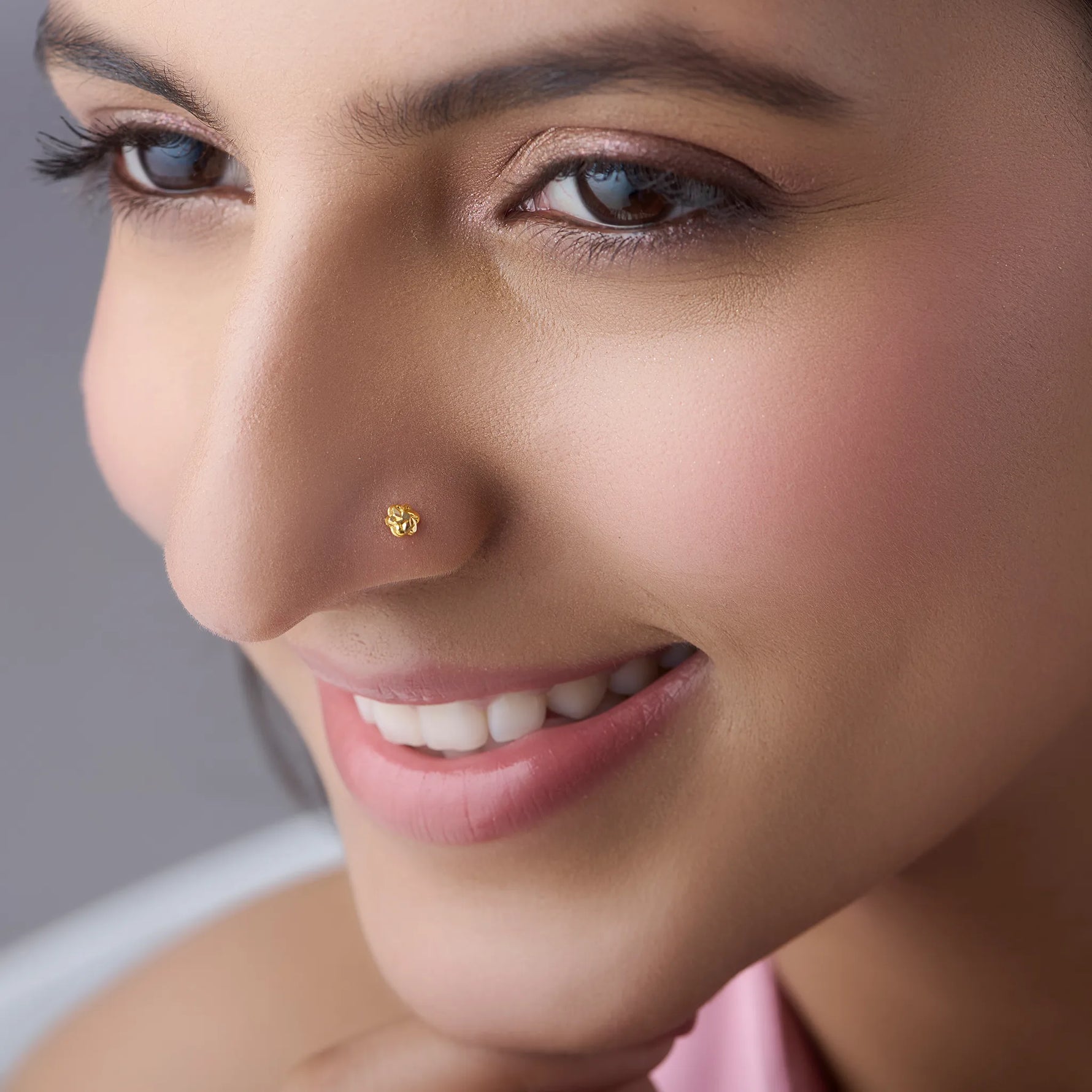 Woman wearing a delicate 18K gold nose pin showcasing an elegant everyday look