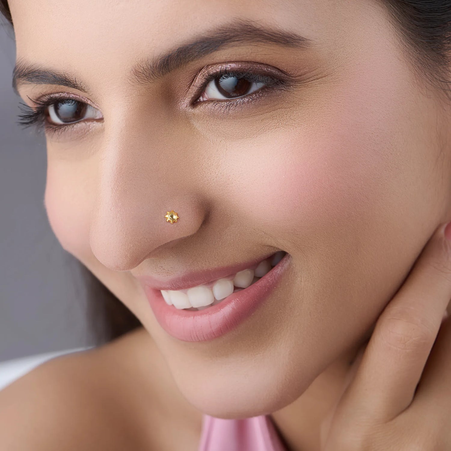 Lifestyle close up of a woman wearing a small gold nose pin showcasing a graceful everyday look